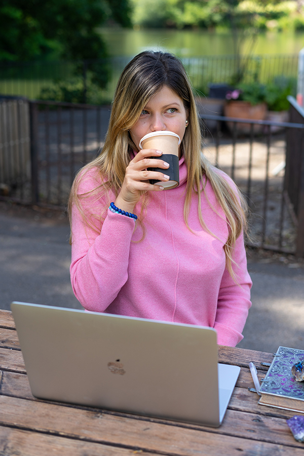 woman enjoying coffee whilst working on her laptop