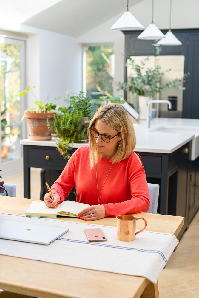 business owner writing in her notebook at kitchen table