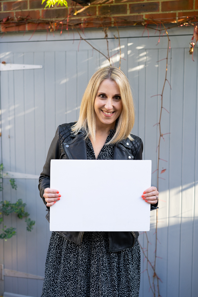 small business owner holding white foam board outside