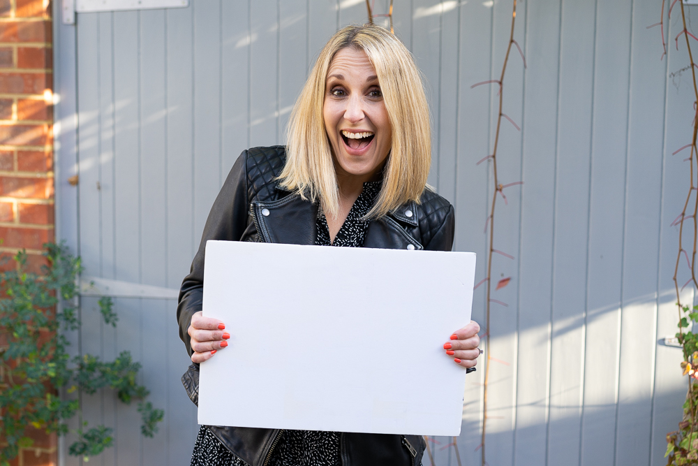 small business owner holding white foam board outside